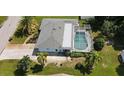 An aerial view of a home with a screened pool, palm trees, and a well-maintained lawn at 221 Malvern Dr, Venice, FL 34293