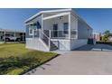 Front view of a single-wide home with a covered porch and a concrete driveway at 127 Nautical Dr, North Port, FL 34287