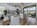 Modern kitchen boasts stainless appliances, mosaic backsplash, granite countertops, island, and serene water views at 235 Cassano Dr, Nokomis, FL 34275