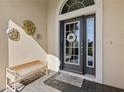 Front entry with decorative door, welcome mat, and bench at 10788 Trophy Dr, Englewood, FL 34223