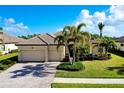 One-story house with tile roof, two-car garage, and palm trees at 20314 Passagio Dr, Venice, FL 34293