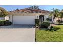 Front view of a single-story home with a white garage door and landscaping at 444 Pinewood Lake Dr, Venice, FL 34285