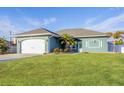 Beautiful teal house with a white garage door and manicured lawn at 5298 Drew Rd, Venice, FL 34293