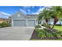 Two-car garage with gray exterior and landscaping, featuring a palm tree and manicured lawn at 21042 Anclote Ct, Venice, FL 34293