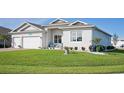 Two-car garage, light gray house, blue door, and landscaped lawn at 9401 President Cir, Port Charlotte, FL 33981