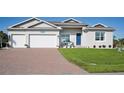 Two-car garage, light gray house, blue door, and landscaped lawn at 9401 President Cir, Port Charlotte, FL 33981