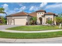 Tan house with tile roof, two-car garage, and manicured lawn at 20909 Duomo Ct, Venice, FL 34293