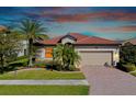 Single-story home with tile roof, palm trees, and brick driveway at dusk at 12704 Richezza Dr, Venice, FL 34293