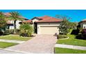 Single-story home with tile roof, palm trees, and brick driveway at 12704 Richezza Dr, Venice, FL 34293