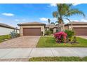 Beautiful single-story home with a well-manicured lawn, colorful flowerbeds, and a brick-paved driveway at 12837 Oriago St, Venice, FL 34293