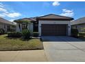 One story home with brown roof, attached garage, and manicured lawn at 624 Silk Oak Dr, Venice, FL 34293