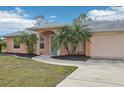 Peach house with teal door and palm trees at 13421 Gershwin Ln, Port Charlotte, FL 33981