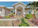 Front entry with arched entryway and lush landscaping at 1558 Belfry Dr, Venice, FL 34292
