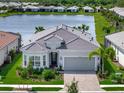 Single-story home with a grey roof and attached garage, nicely landscaped and located by a lake at 25509 Royal Tern Ln, Englewood, FL 34223