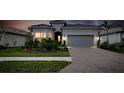House exterior at dusk featuring a two-car garage and well-maintained landscaping at 25509 Royal Tern Ln, Englewood, FL 34223