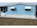 Charming blue single-story home featuring awnings, a well-maintained yard, and an attached carport at 356 Longwood Dr, Venice, FL 34285