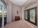 Covered front porch with tiled floor, bench, and double doors at 498 Lake Of The Woods Dr, Venice, FL 34293