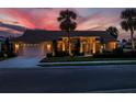 Well-lit home with a two-car garage and landscaped yard at dusk at 1579 Waterford Dr, Venice, FL 34292