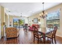 Spacious living room with wood floors, ceiling fan, dining area, and expansive lake views through large windows at 1841 Batello Dr, Venice, FL 34292