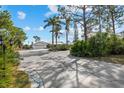 Spacious driveway leading to a well-maintained home featuring mature landscaping and exterior lighting at 38 Riverfront Dr, Venice, FL 34293