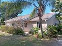 Tan house with landscaped yard and palm tree in partial view, under a clear blue sky at 601 E Seminole Dr, Venice, FL 34293