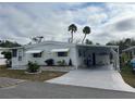 Front view of a white manufactured home with covered patio and palm trees at 607 Cervina Dr, Venice, FL 34285