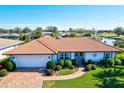 Charming single-story home features a red tile roof, manicured landscaping, and an attached two-car garage at 1008 Burning Oak Ct, Venice, FL 34293