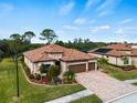Two-story house with tile roof, paver driveway, and mature trees at 12950 Basilica Dr, Venice, FL 34293