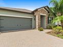 Modern two-car garage with a paver driveway at 13237 Satin Lily Dr, Riverview, FL 33579