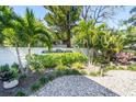 Property entrance with manicured landscaping, palm trees, and white privacy wall at 1555 Tarpon Center Dr # 238, Venice, FL 34285