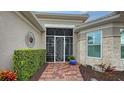 Front entry with screened-in porch, brick walkway, and lush landscaping at 19500 Petrino St, Venice, FL 34293