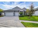 Two-story house with gray siding, three-car garage, and landscaped yard at 19807 Bridgetown Loop, Venice, FL 34293