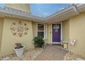 Home's entrance with a purple door and landscaping at 518 Boxwood Ln, Englewood, FL 34223