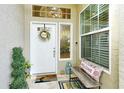 Front entry with white door, welcome mat, and decorative bench at 560 Fallbrook Dr, Venice, FL 34292