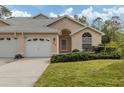Tan stucco home with white garage door, landscaping, and arched entryway at 826 Bayport Cir, Venice, FL 34292