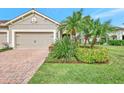 Tan house with tile roof, landscaping, and a three-car garage at 11409 Okaloosa Dr, Venice, FL 34293