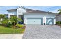 White house with light blue garage doors and a paver driveway at 12460 Davie Ct, Venice, FL 34293
