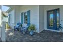 Front porch with blue chairs, a table, and potted plants at 12460 Davie Ct, Venice, FL 34293