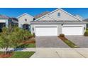 Two-car garage, gray exterior, landscaping, and a paved driveway at 12488 Palatka Dr, Venice, FL 34293