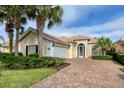 Tan two-story house with tile roof, white garage door, and landscaped yard at 13240 Guyana St, Venice, FL 34293