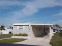Tan mobile home with carport, landscaping, and partial view of neighboring homes at 516 Ashwood Dr, Venice, FL 34285