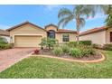 Tan single-story house with a brick driveway and landscaped yard at 9895 Wingood Dr, Venice, FL 34292