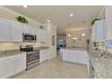 Modern kitchen with white cabinets, granite counters, and stainless steel appliances at 9895 Wingood Dr, Venice, FL 34292