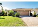 House with a two-car garage and a brick driveway at 107 Corte Del Rosa, Venice, FL 34285