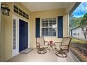 Small front porch with two wicker chairs and a small table at 1655 Lancashire Dr # 1655, Venice, FL 34293