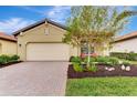 Tan house with a light beige garage door and red chairs at 24165 Spartina Dr, Venice, FL 34293