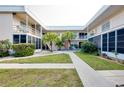 Two-story condo building with lush landscaping and walkway at 460 Base E Ave # 122, Venice, FL 34285