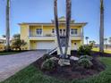 Charming yellow two-story home with a metal roof, covered balcony, and tropical landscaping at 1784 Bayshore Dr, Englewood, FL 34223
