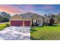 A charming home boasts a red two-car garage and meticulously manicured landscaping at 2737 Cottage Ln, North Port, FL 34286