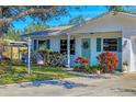 Inviting home entrance featuring a well-manicured lawn, turquoise door, and lush landscaping adding curb appeal at 3151 Datura Rd, Venice, FL 34293